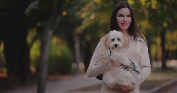 秋の公園で彼女の犬を保持している女性の肖像画カメラを見て スローモーション — ストック動画