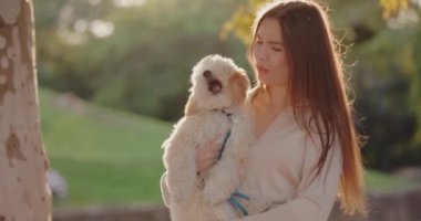 Sonbahar parkında köpeğini tutan kadının portresi, ağır çekimde esniyor.