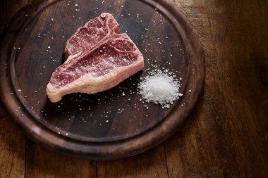 Ahşap arka planda baharatlı çiğ biftek.