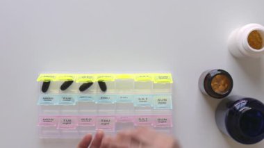 Kadın ilaç kutusunu dolduruyor. Arka planda haplar olan şişeler. Sağlık sigortası