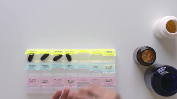 Woman fills the pillbox. Bottles with pills on background. Healthcare medicine — Stock Video