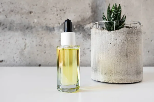 Close-up facial oil yellow serum glass bottle with pipette and succulent