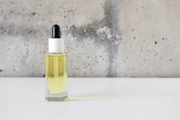 Natuurlijke gezicht serum glazen fles met pipet op witte bureau op cement muur achtergrond — Stockfoto