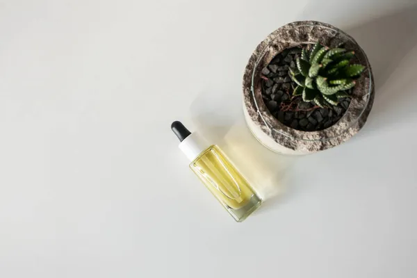 Olejek do twarzy butelka szklana z pipetą na białym tle biurka — Zdjęcie stockowe
