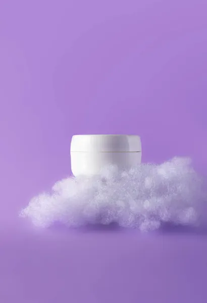 Blanco cosmetische huidverzorging make-up pot met pluizige wolken op violet. Concept zorg met gevoelige huid. Creatief stilleven foto, verticaal — Stockfoto