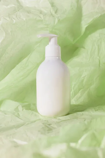 Botella de loción cuidado de la piel belleza producto cosmético en papel desmenuzado verde. Champú, jabón, acondicionador de cabello en blanco maqueta vacía — Foto de Stock