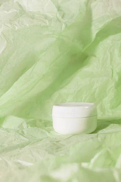 Crema botella cuidado de la piel belleza producto cosmético en papel desmenuzado verde — Foto de Stock