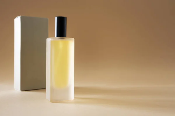 Parfum fles en verpakking doos op beige achtergrond met kopieerruimte — Stockfoto