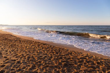 Sarı kumda gün batımında el salla. Hazar Denizi.