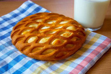Orijinal cheesecake. Süzme peynirli turta. Kremalı hamur işleri ve bir bardak süt. Kareli peçetede Paskalya tatlısı.