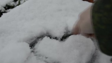 Karda kalp. El beyaz karın üzerine bir kalp çizer..