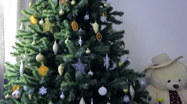 Christmas tree with toys and lanterns. Christmas, winter, New Year. A large teddy bear in a straw hat.