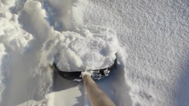 Evin yakınındaki kar yığınlarını kar küreğiyle temizliyorum..