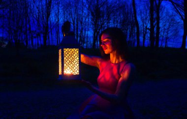 Pembe elbiseli, karanlık bir ormanda bir kız. Ormanda feneri olan genç bir kız. Güzel orman. Arkaplan.