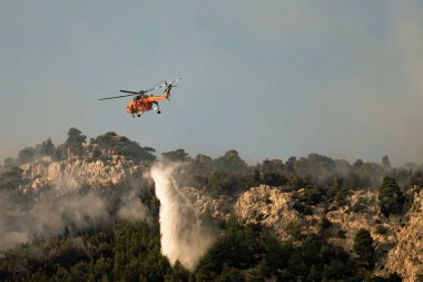 Loutraki, Yunanistan 14 Eylül 2019. İtfaiye helikopteri Sikorsky S-64 Yunanistan 'ın Loutraki şehrinde gökyüzünde yangına su püskürtüyor..