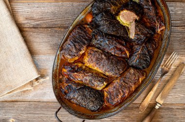 Kahverengi soslu lahana dolması. Lezzetli lahana ruloları ile doldurulmuş lezzetli geleneksel Alman yemeği. Lezzetli kıyma ile doldurulmuş ve ahşap masanın üzerinde, kırsal bir güveçte lezzetli bir kahverengi sosta servis edilmiş. Kopyalama alanı ile genel görünüm