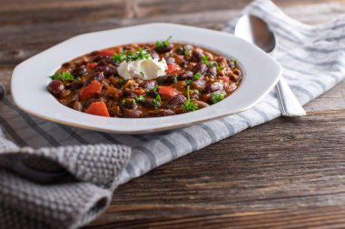 Fasulyeli güveç, sebze ve kıyma. Lezzetli Meksika ya da Tex Meksika fasulyesi güveci sebze ve kıyma ile pişirilir. Tahta masada bir tabakta servis edilmiş. kaşıkla