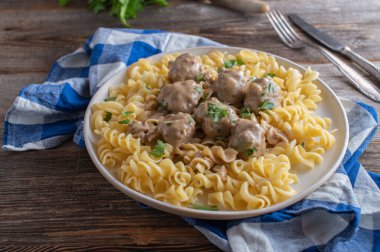 Pasta with meatballs and sauce. Traditional kttbullar, swedish meatballs with fusilli noodles and cream sauce. Fresh and homemade cooked. Served on a plate on rustic and wooden table.