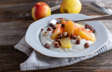 Grain free and gluten free breakfast bowl for dieting with a low fat icelandic skyr topped with sauteed apples and roasted hazelnuts