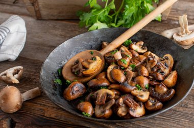 Pan fried mushrooms cooked with butter, herbs, pepper and salt. Served in a rustic cast iron pan on wooden table