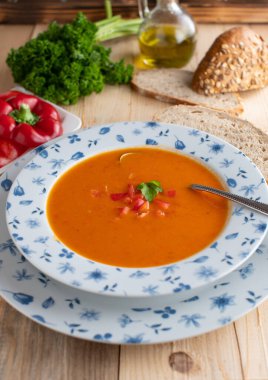 Kırmızı dolma biber çorbası taze ve ev yapımı ahşap masa arkasında kırsal bir kasede servis ediliyor. Dikey resim