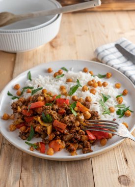 Kızarmış biftek, lahana, sebze ve kızarmış bezelye ile glütensiz yemek. Ahşap masa arkasında beyaz bir tabakta basmati pilavı ile servis edilir. Yakın çekim ve dikey resim.