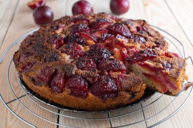 Erikli meyveli pasta. Ahşap masada izole edilmiş soğutma rafında servis edilen ev yapımı taze baş aşağı erikli kek..