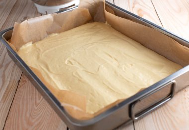 Pişirmek için hamur işi. Taze ve ev yapımı sünger kek tabağı ahşap masa arkasında kare bir fırın tavasında servis edilir.
