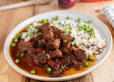 Pirinç ve sebzeli güveç. Baharatlı tavuk göğsü güveci ve taze bezelye ve basmati ile servis edilen ev yapımı sağlıklı yemek, bir tabak yaban pirinci..