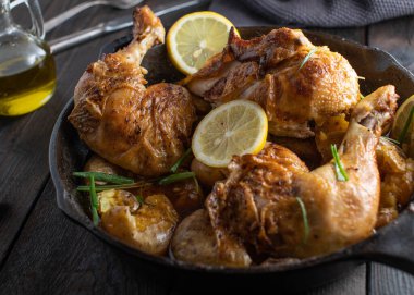 Soslu tavuk budu ve patates. Lezzetli Akdeniz fırını. Koyu ahşap masa üzerinde kırsal dökme demir bir tavada servis ediliyor. Yakın çekim ve ön görüş. Yemek hazır.
