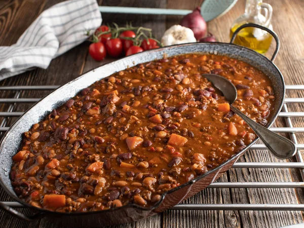 Rustic bean stew with minced meat and sweet potatoes. Tex mex food with a delicious and spicy bean stew alla chili con carne. Cooked with ground beef and sweet potatoes. Served in a rustic skillet on wooden table. Ready to eat.
