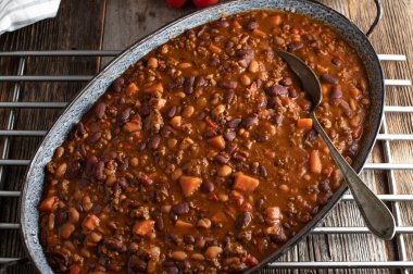 Tatlı patatesli Chili con carne. Lezzetli ev yapımı fasulye güveci alla chili con carne kıymalı ve tatlı patatesli. Ahşap masada, tepeden bakıldığında kırsal bir tavada servis edilmiş.