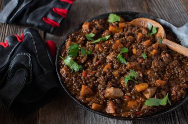 Lezzetli bir tavuk yahnisi, mercimek ve sebzeli Fitness Yemeği. Yüksek proteinli yemek. Ahşap masa arkasında kırsal bir tavada servis edilmiş.