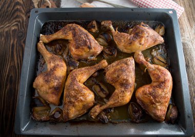 Ev yapımı taze kavrulmuş ya da fırında pişmiş tavuk bacağı. Soğanla pişirilmiş ve mutfak masasının arkasındaki yemek tepsisinde servis edilmiş. Yemek hazır.