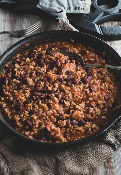Healthy fitness food with a vegan or vegetarian muscle building meal. Cooked with brown rice, kidney beans, vegetables and tomato sauce. Served in frying pan on rustic table background from above,