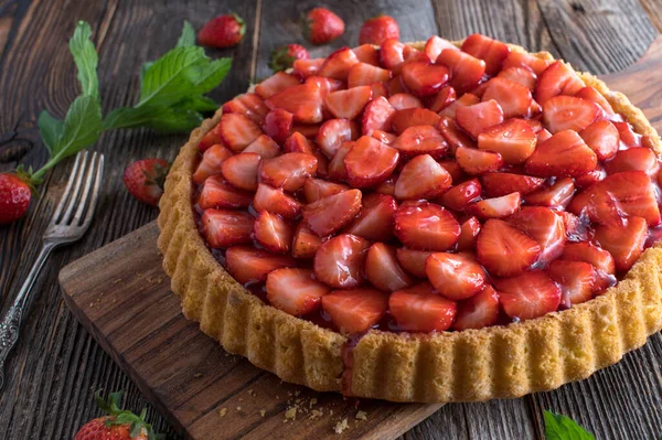 Strawberry pie on wooden table. Traditional german fruitcake with strawberries. Served isolated on wooden table background. Closeup with copy space