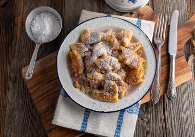 Kaiserschmarrn. Geleneksel taze ve ev yapımı. Köy ve ahşap masa zemininde eski moda tabakta servis ediliyor. Kopyalama alanı olan üst görünüm. 