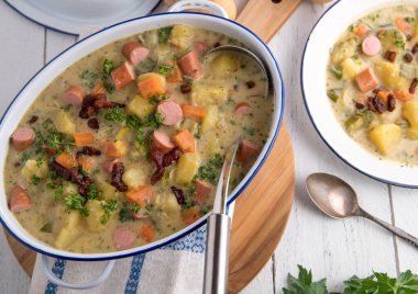 Lezzetli patates çorbası ya da patates yahnisi. Taze ve ev yapımı. Beyaz masa arkasında eski usul güveç tenceresinde servis edilmiş. Üst görünüm