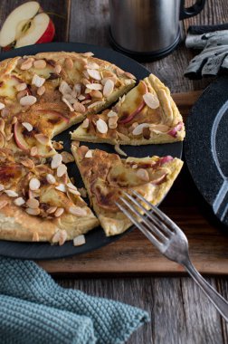 Yumurta ve yulaf ezmesi ile pişirilmiş sağlıklı fitness protein krepi. Elmayla pişirilmiş ve üstüne kavrulmuş badem konmuş. Spor beslenme yemeği. Dambıl ile ahşap masada servis edilir..