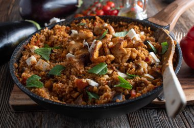 Patlıcan, sebze, tavuk eti ve peynirli Akdeniz pirinç yemeği. Sağlıklı bir tencere aile yemeği. Ahşap masa arkaplanında yemeye hazır.. 