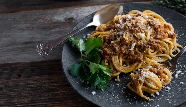 Spaghetti Alla Bolognese Servito Piatto Nero Con Parmigiano Sfondo Rustico — Foto Stock