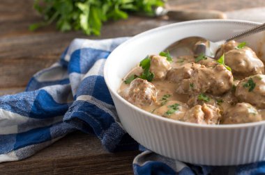 Geleneksel ve ev yapımı taze İsveç köftesi, krema soslu kttbullar. Kırsal ve ahşap masa zemininde çay havlusunda kaşıkla beyaz bir kutuda servis edilmiş. Kopyalama alanı ile yakınlaştır ve yan görünüm