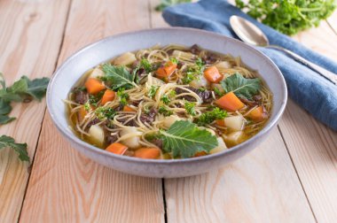 Kâsede ev yapımı taze etli şehriye çorbası. Ahşap masa arkaplanında kopya alanı ile izole edilmiş. Sağlıklı beslenme