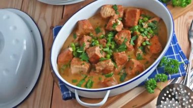 Fresh and homemade cooked goulash or ragout with poultry meat and a delicious cream sauce. Served on wooden table background and is garnished with parsley.