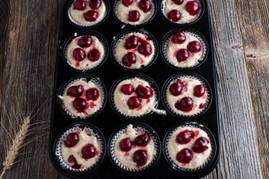 Ahşap masa arkasında izole edilmiş kek kutusunda kirazlı taze kek hamuru. Yakın çekim ve üst görünüm