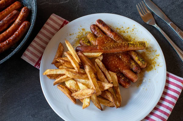 Vienna sausages with homemade french fries and spicy curry sauce on a plate.