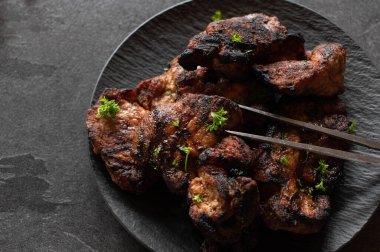 Tabakta ızgara domuz bifteği. Koyu arka planda izole edilmiş et çatalıyla servis edilen taze ızgara domuz boynu ve fotokopi alanı.