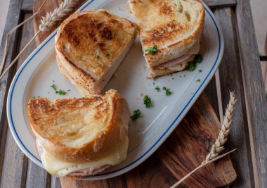 Plate with sandwiches. Pan fried baguette with ham and cheese served on wooden background
