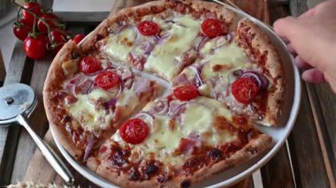 A Piece of pizza is taking from a plate by womans hand
