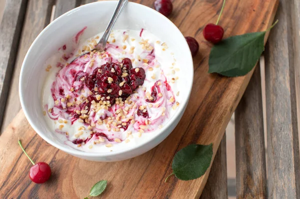 Protein breakfast bow with gree yogurt, sugar free sour cherry compote and roasted hazelnuts. Served in a bowl on rustic and wooden table background